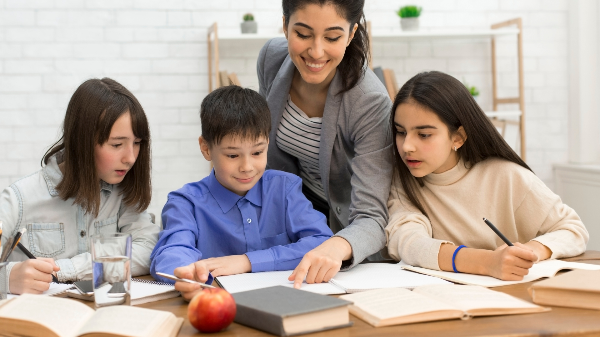 a group of students and their teacher looking at schoolwork
